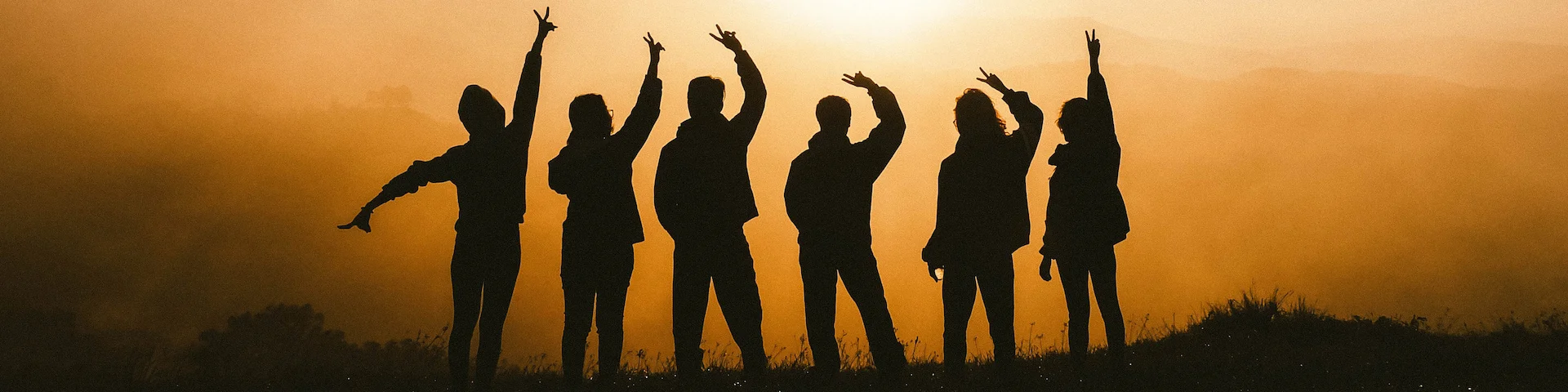 photo of 6 people in
      silhouette against a sunrise in the mountains